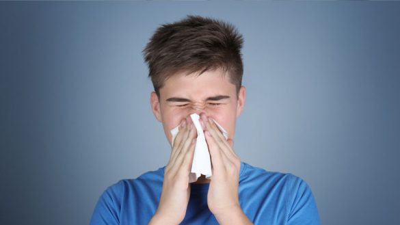 Young man blowing nose in tissue