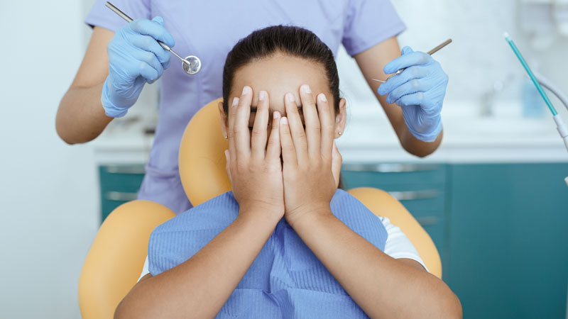 Mulher corbindo o rosto com medo do dentista